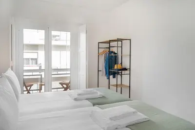 a white bedroom with a bed with towels on it at Faro DAZ House by Get Your Stay in Faro