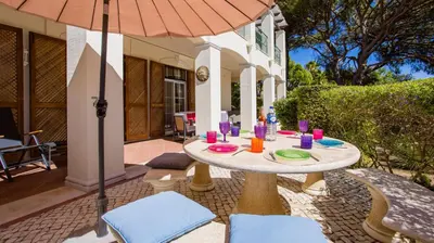 a table with chairs and an umbrella on a patio at 3Br Apt-Quinta do Lago-Private Terrace in Quinta do Lago