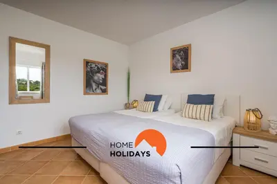 a bedroom with a large bed with a home holidays sign on it at #294 T2 Com Amplo Terraço by Home Holidays in Albufeira