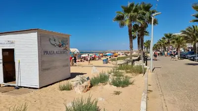 a small building on a beach with a crowd of people at Beach, please! in Quarteira
