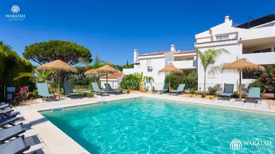 a pool with chairs and umbrellas in front of a building at Apartment Lamine in Loulé