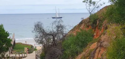 a sail boat in the ocean next to a beach at Alfamar e Falésia in Albufeira