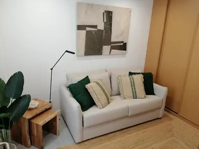 a living room with a white couch with green pillows at Casa Corisca - stylish, cosy, top location in the heart of Faro in Faro