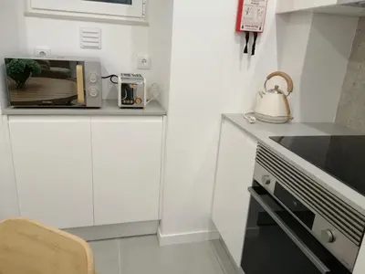 a white kitchen with a microwave and a tea kettle at Casa Corisca - stylish, cosy, top location in the heart of Faro in Faro