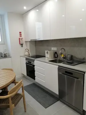 a kitchen with white cabinets and a sink and a table at Casa Corisca - stylish, cosy, top location in the heart of Faro in Faro
