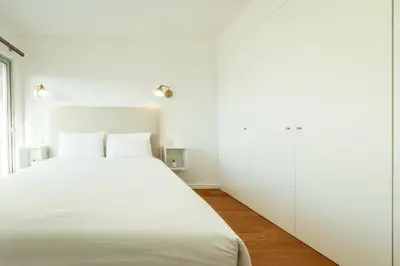 a white bedroom with a large bed and a window at The Green Escape Albufeira Poolside Retreat in Albufeira