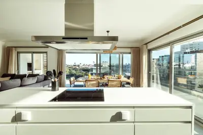 a kitchen with a white counter and a living room at The Green Escape Albufeira Poolside Retreat in Albufeira