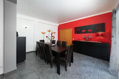 a dining room with a table and a red wall at Casa Coelho in Albufeira