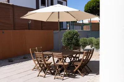 a wooden table and chairs with an umbrella at Casa Coelho in Albufeira