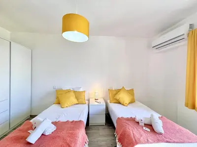 two beds in a small room with yellow and white at Quarteira Brightness by Homing in Quarteira