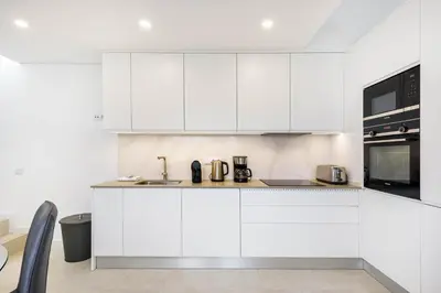 a white kitchen with a sink and a microwave at Casa Bella in Loulé