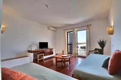 a room with two beds and a desk with a television at BeGuest Oura Vilanova Apartment in Albufeira