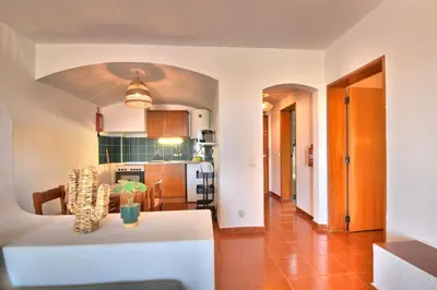 a kitchen and a living room with a white table at BeGuest Oura Vilanova Apartment in Albufeira