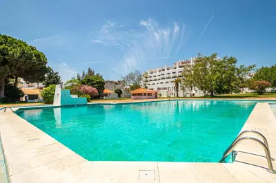 a swimming pool with blue water in front of a building at BeGuest Oura Vilanova Apartment in Albufeira