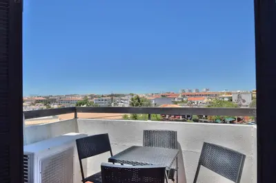a balcony with a table and chairs and a television at BeGuest Oura Vilanova Apartment in Albufeira