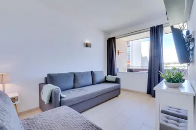 a living room with a blue couch and a window at T1 Edificio Loulé - centro de Vilamoura in Vilamoura