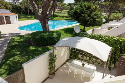 an outdoor patio with an umbrella next to a pool at BmyGuest - Vilamoura Golf Villa in Vilamoura