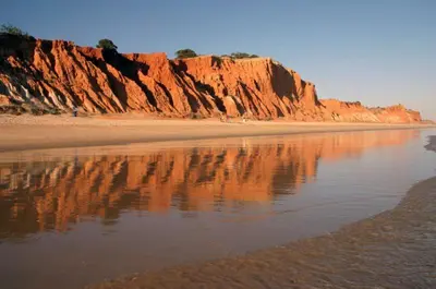 a beach with a reflection of a cliff in the water at Sofisticado Apartamento 3 quartos, terraço privado in Albufeira