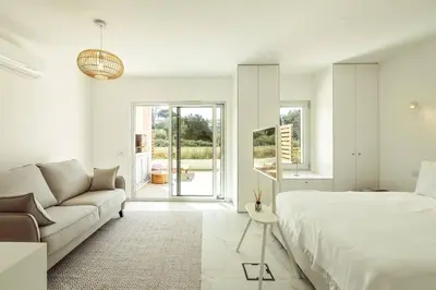 a white bedroom with a bed and a couch at Green View Studio with Pool in Albufeira