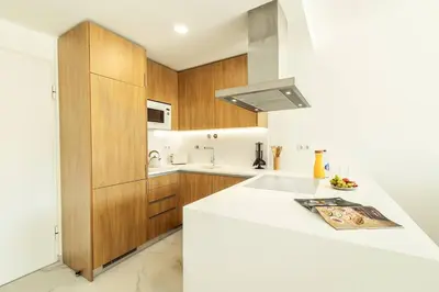 a kitchen with a white counter top and wooden cabinets at Green View Studio with Pool in Albufeira