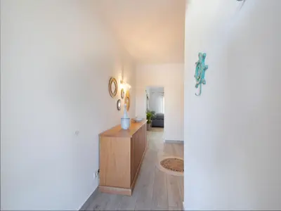 a hallway with a wooden cabinet and a clock on a wall at Boho house, Albufeira in Albufeira