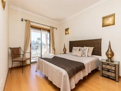 a bedroom with a bed and a chair and a window at NEW! Villa Balaia K-11 in Branqueira