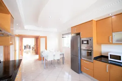 a kitchen with wooden cabinets and a table and chairs at Villa Cinema - Perfect Union in Albufeira