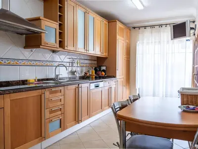 a kitchen with wooden cabinets and a table with chairs at Oura Sunrise 3B Apartment by Stay ici Algarve Holiday Rental in Albufeira