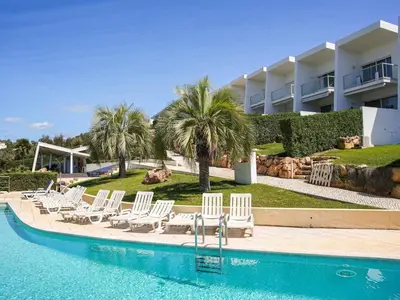 a group of white chairs and a swimming pool at Serenity 03 House by Stay ici Algarve Holiday Rental in Albufeira