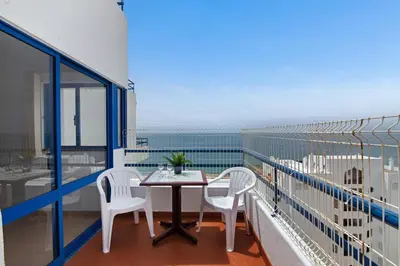 a balcony with a table and chairs and a view of the ocean at T2 2 Linha Praia Vista Mar in Quarteira