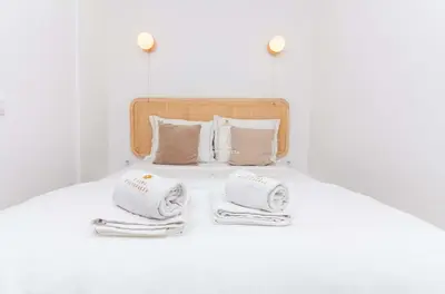 a white bed with towels and pillows on it at Apartamento Mare Aveiros Beach in Albufeira
