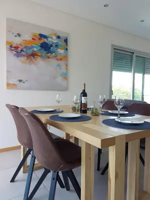 a wooden table with chairs and a bottle of wine at Modern apartment on the beach of Falesia in Albufeira