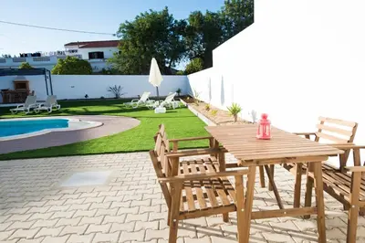 a wooden table and chairs next to a pool at Rosa Lilás in Boliqueime