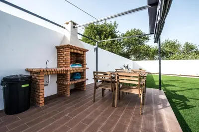 a patio with a fireplace and a table and chairs at Rosa Lilás in Boliqueime