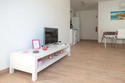 a living room with a tv on a white cabinet at Rosa Lilás in Boliqueime