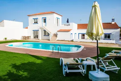 a villa with a swimming pool in front of a house at Rosa Lilás in Boliqueime