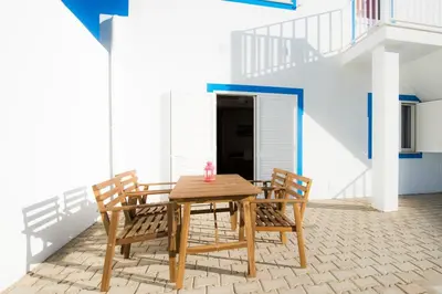 a wooden table and chairs in a room with a staircase at Rosa Lilás in Boliqueime