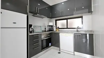 a kitchen with black cabinets and a white refrigerator at Albufeira, Blue Wave Retreat 65 in Albufeira