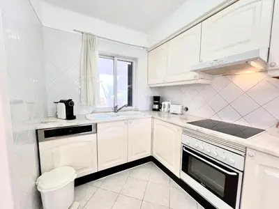 a white kitchen with white cabinets and a window at Albufeira Balaia Golf Vilage 7 With Pool by Homing in Albufeira