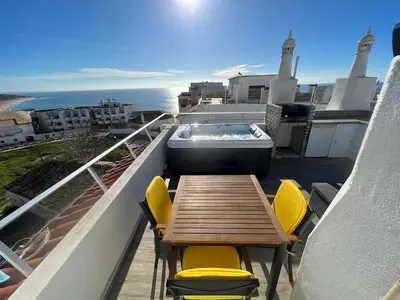 a table and chairs on a balcony with a bath tub at Casa rooftop jacuzzi and magnificent sea view in Albufeira