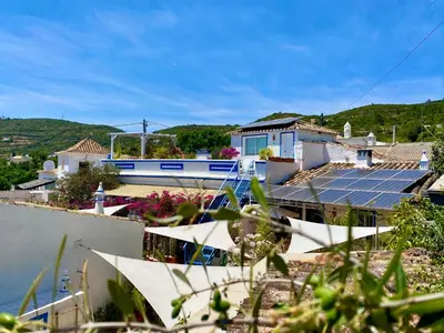 two blue lounge chairs and an umbrella and a bird cage at Casa da Aldeia in Santa Bárbara de Nexe