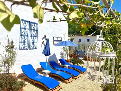 a patio with two white chairs and potted plants at Casa da Aldeia in Santa Bárbara de Nexe