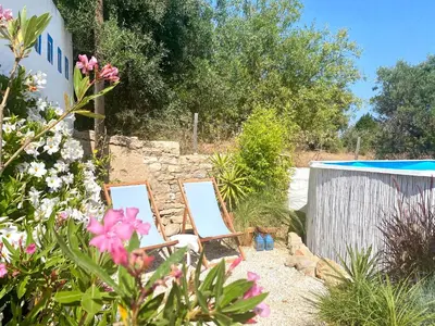 a row of blue chairs with an umbrella at Casa da Aldeia in Santa Bárbara de Nexe