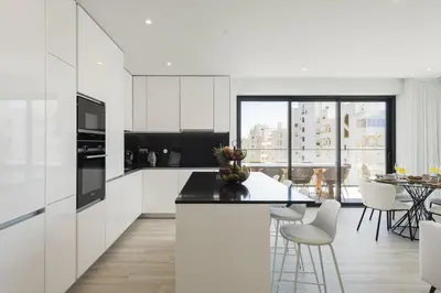 a kitchen with white cabinets and a table with chairs at Terracos de Quarteira II White by Real Properties in Cavacos