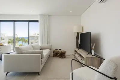 a white living room with a couch and a tv at Terracos de Quarteira II White by Real Properties in Cavacos
