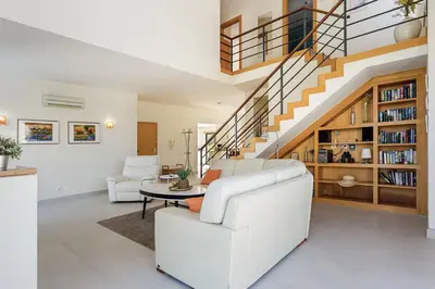 a living room with white furniture and a staircase at Casa Peva in Albufeira