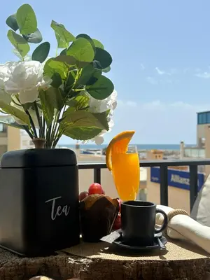a table with a vase of flowers and a cup of coffee at Beach Holidays in Quarteira