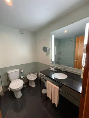 a bathroom with two sinks and a toilet and a mirror at Hotel Vila Galé Cerro Alagoa in Albufeira
