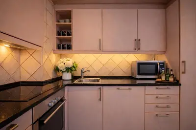 a kitchen with white cabinets and a sink and a microwave at Ocean Bliss - Panoramic Sea View - 20m to Beach - 2 Swimming Pools - Private Parking in Albufeira