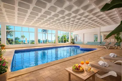 a pool in a living room with a table and chairs at Ocean Bliss - Panoramic Sea View - 20m to Beach - 2 Swimming Pools - Private Parking in Albufeira
